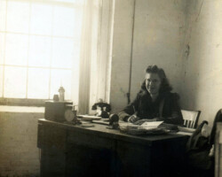 Sylvia Gerard, office clerk, Plymouth Sportswear Company, Inc., Fall River, Massachusetts, posing at her desk, 1940.